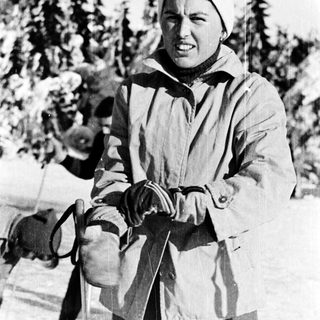 Woman in winter attire, holding ski poles.