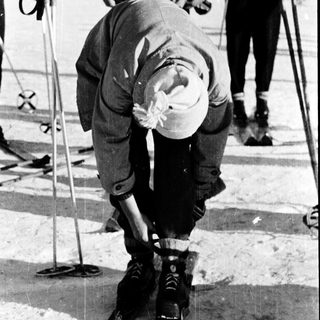 Ski racer bending forward in competitive downhill skiing.