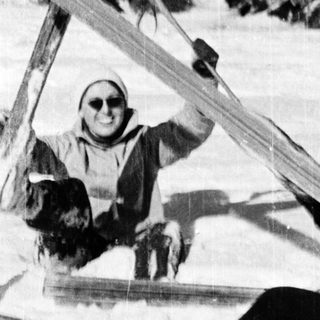 Two people skiing on snow, one lying down.