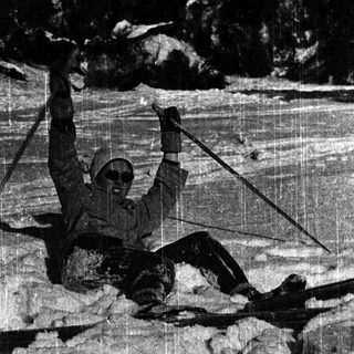 Person skiing downhill with arms raised.