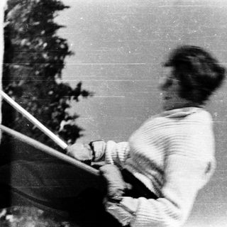 Person skiing downhill in snowy forest.