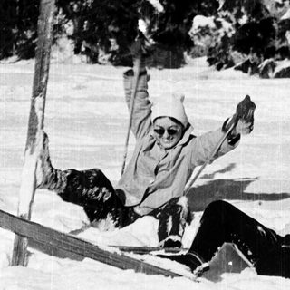 People skiing downhill, one falling dramatically.
