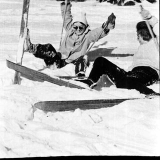 People skiing downhill, one falling dramatically.