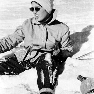 Person skiing in snowy terrain wearing sunglasses and winter gear.