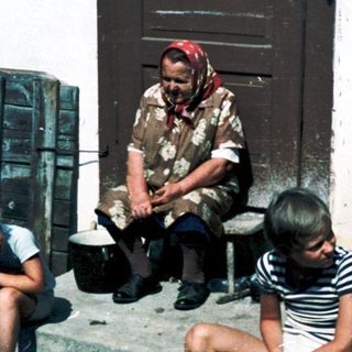Children and adult near rustic building.