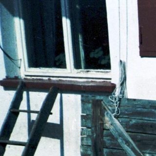 Children and adult near rustic building.
