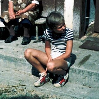 Children and adult near rustic building.
