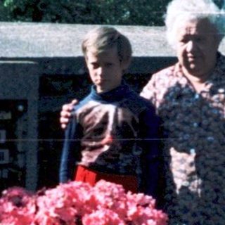 Family tending gravesite with flowers in cemetery.