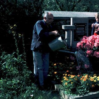Family tending gravesite with flowers in cemetery.