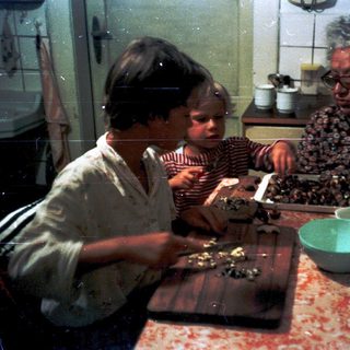 Two children and an adult preparing food together.