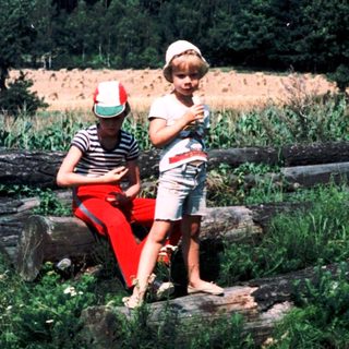 Two people sitting on rocks in a rural field.