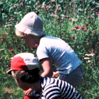 Two people picking flowers in a field.
