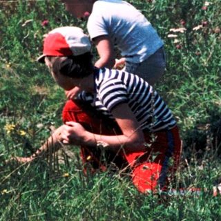 Two people picking flowers in a field.