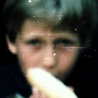 Two children eating bread through a window.