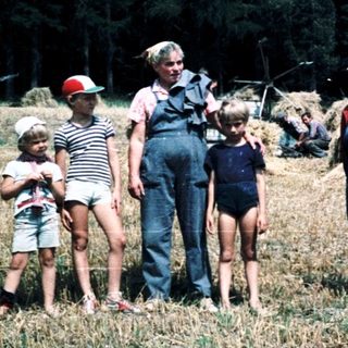 Family posing with horse-drawn hay wagon in rural field.