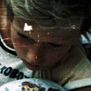 Child reading outdoors on a blanket.