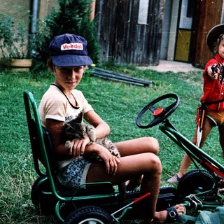 Two children playing with toy vehicles outdoors.
