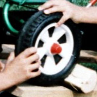 Three children playing with toy cars on grass.