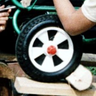 Three children repairing a toy wagon outdoors.