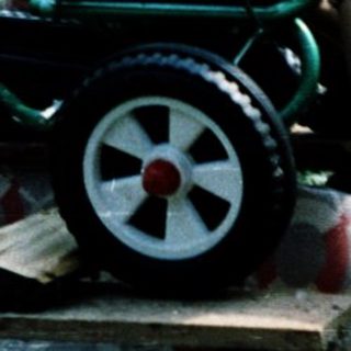 Three children playing with homemade toy cart.