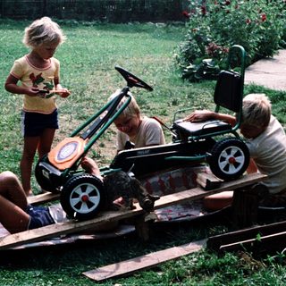 Two adults and a child building a toy train on wooden tracks.