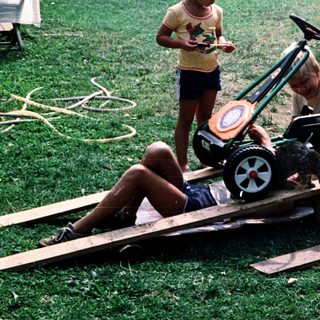 Two adults and a child building a toy train on wooden tracks.
