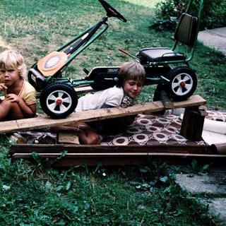 Two children playing with toy lawn mowers.
