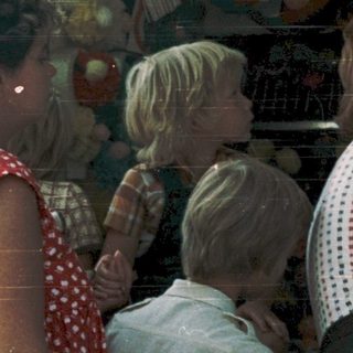 Family examining colorful toy display at outdoor market.