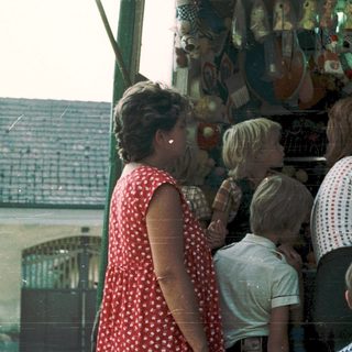 Family examining colorful toy display at outdoor market.