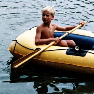 Two people rowing on an inflatable boat in water.