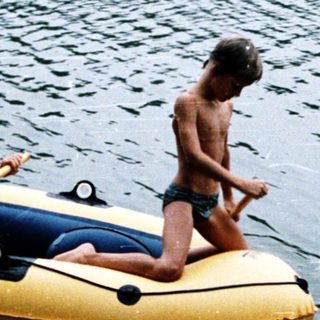 Two people rowing on an inflatable boat in water.