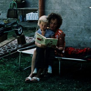Two children reading outside near toy car.