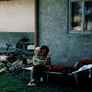 Two children reading outside near toy car.