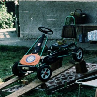 Two children reading outside near toy car.