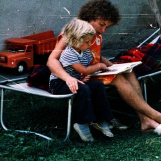 Two people reading outdoors on folding chairs.