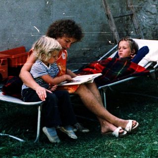 Two people reading outdoors on folding chairs.