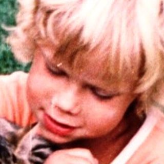 A child plays with a cat on a blue exercise ball.