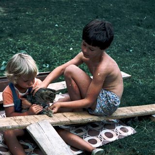 Two children playing with a cat on a boat.