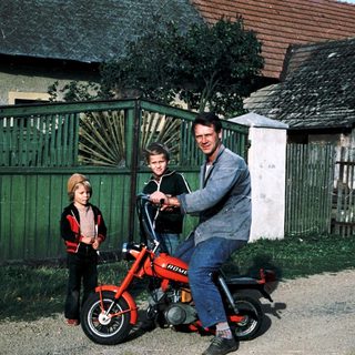 Family posing with vintage red motorcycle.