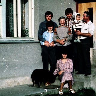 Family group posing outside a house with dog.