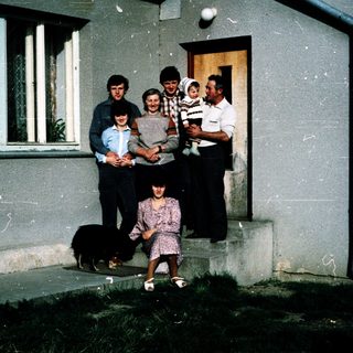 Family group posing outside a house with dog.