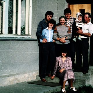 Family posing together outside a house.