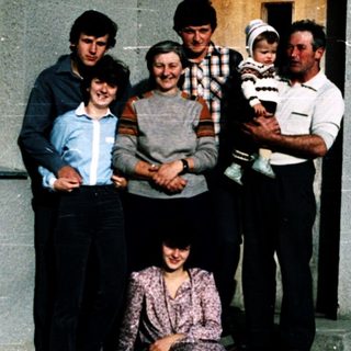 Family posing together outside a house.