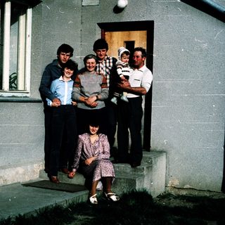 Family posing together outside a house.
