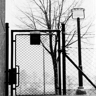 Fenced entrance gate with security camera and lamp post.