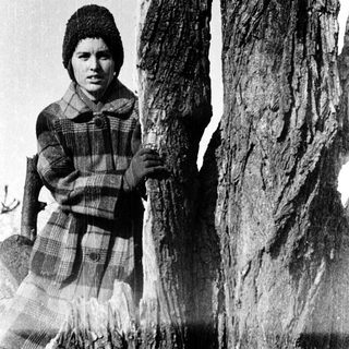 Young girl standing beside weathered stone pillars.