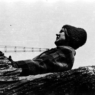 Person climbing rocky cliff wearing winter attire.