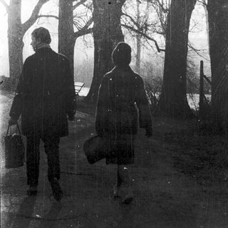 Two people walking in a forest path.