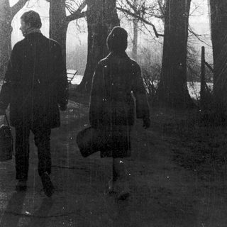 Two people walking in a forest path.