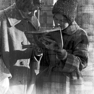 Two people reading together indoors during winter.